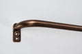A close-up of a curved brass rod with a matching wall bracket, finished in a warm bronze color, set against a plain light gray background.