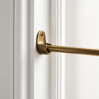 A close-up of a brass door rod mounted on a white paneled door frame.